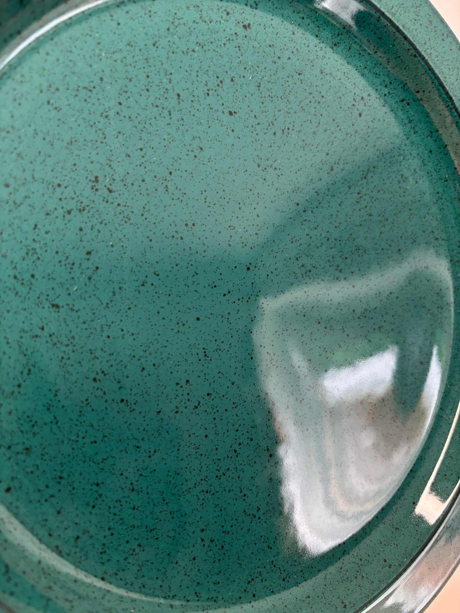 Close-up of a teal ceramic plate with speckled pattern