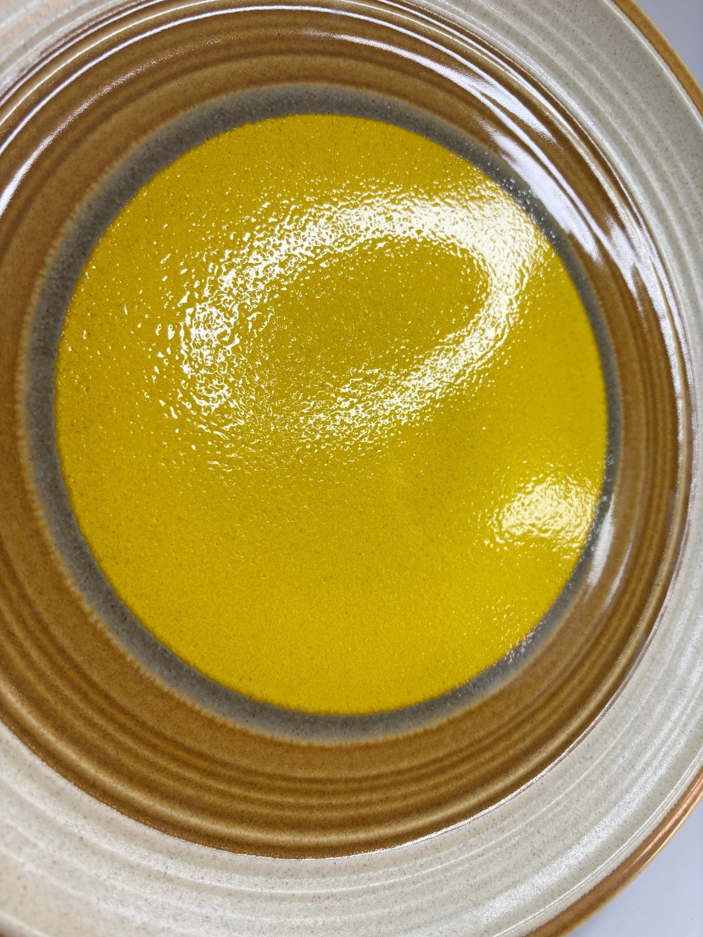 Close-up of a ceramic plate with a yellow center and brown rim