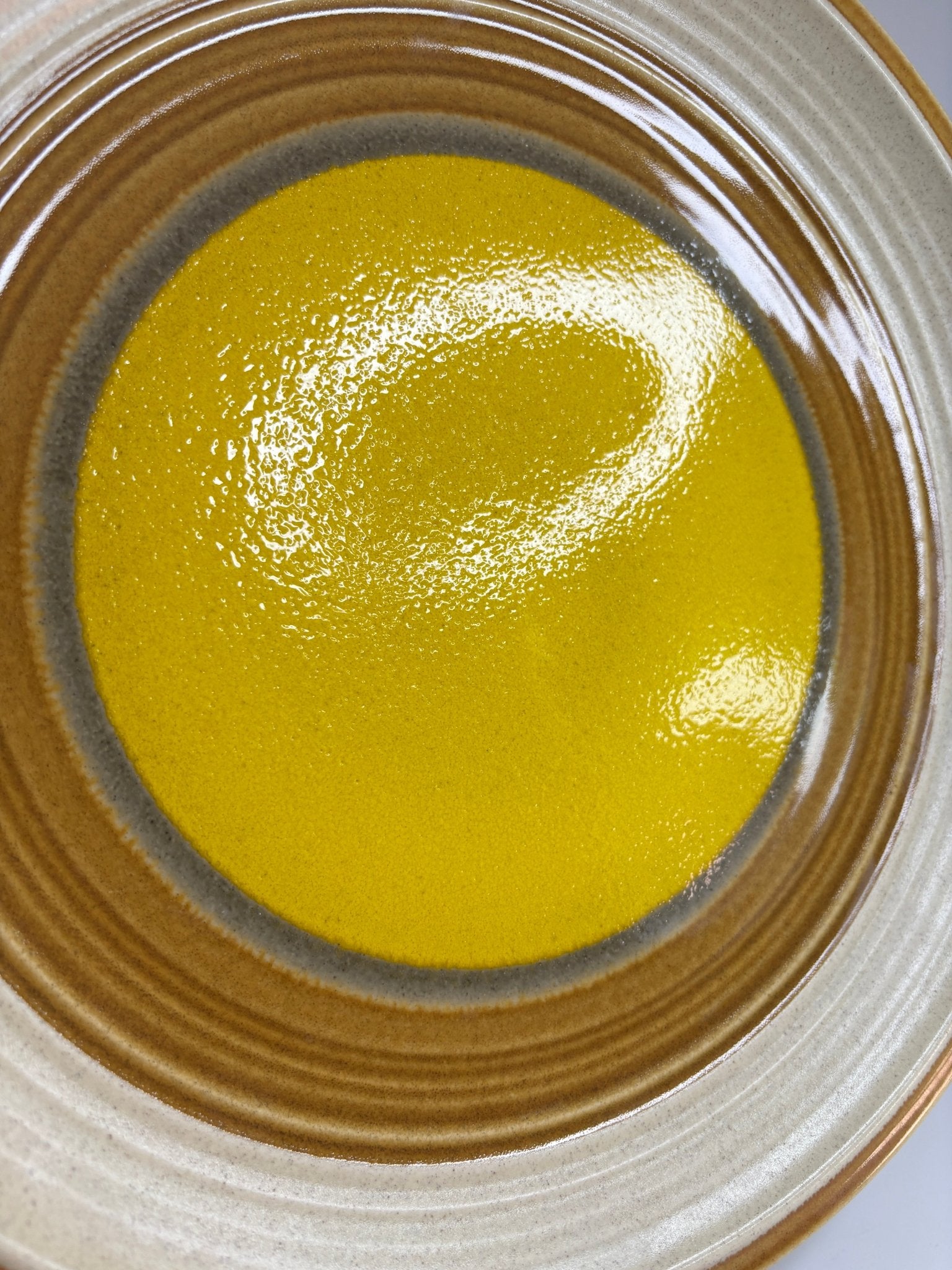 Close-up of a ceramic plate with a yellow center and brown rim