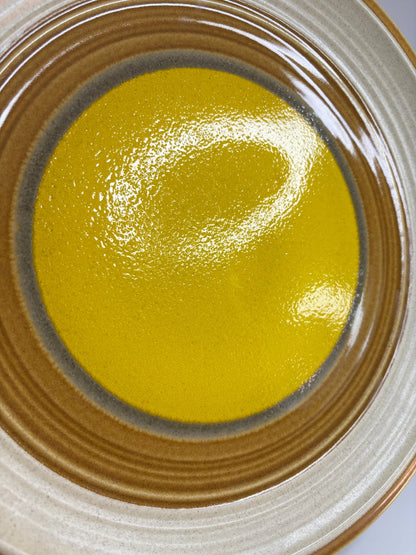 Close-up of a ceramic plate with a yellow center and brown rim