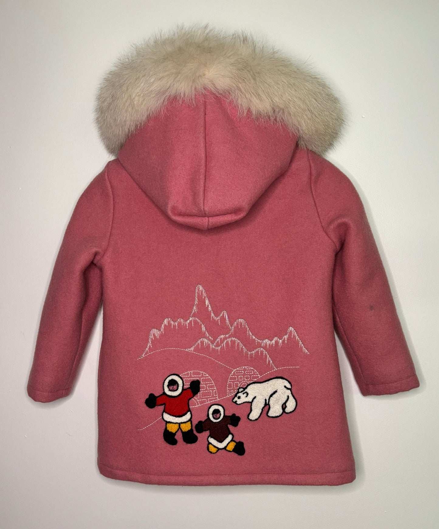 Pink children's coat with a hood and mountain and polar bear design on the back, on a light gray background.