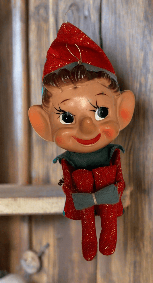 Vintage-style elf figurine with a red hat and outfit on a wooden background