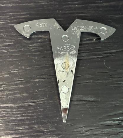 Metal triangular tool with 'ABS' marking on a dark surface