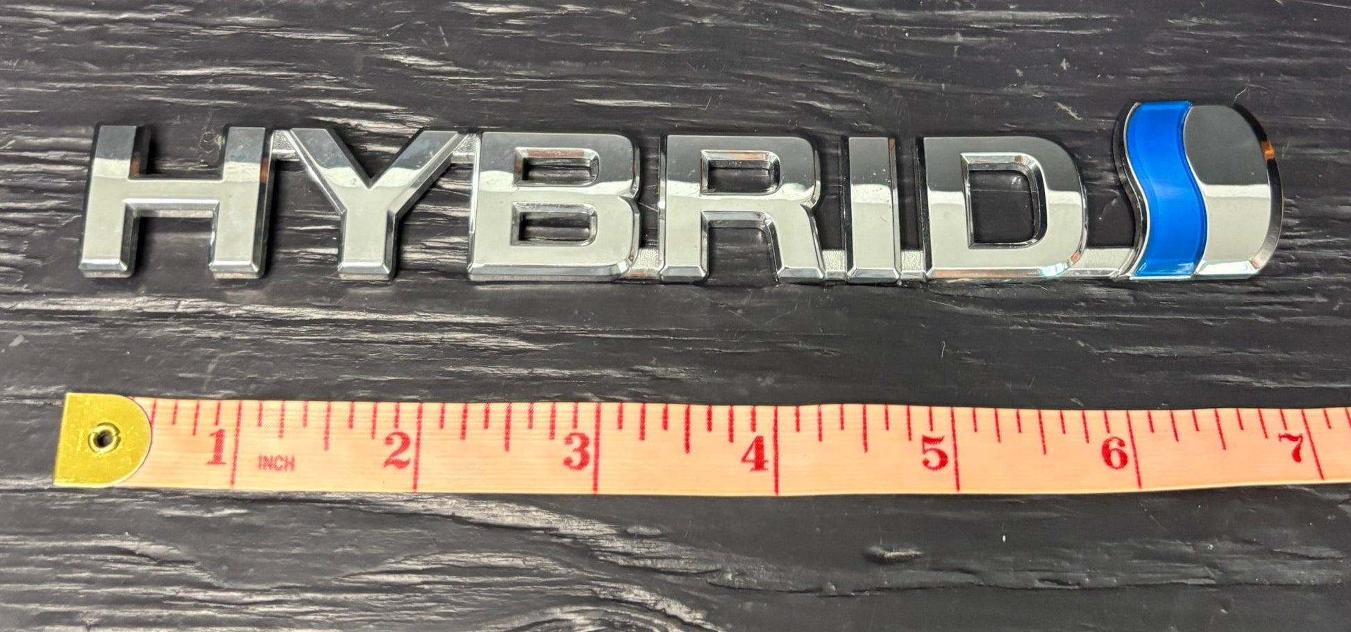 Hybrid emblem with a ruler for scale on a dark background